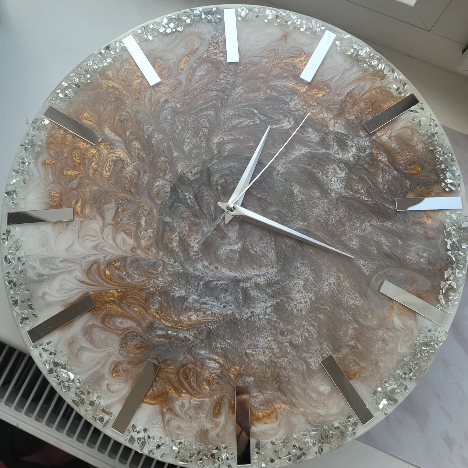 Decorative wall clock with a glass face and metallic design on a white surface.