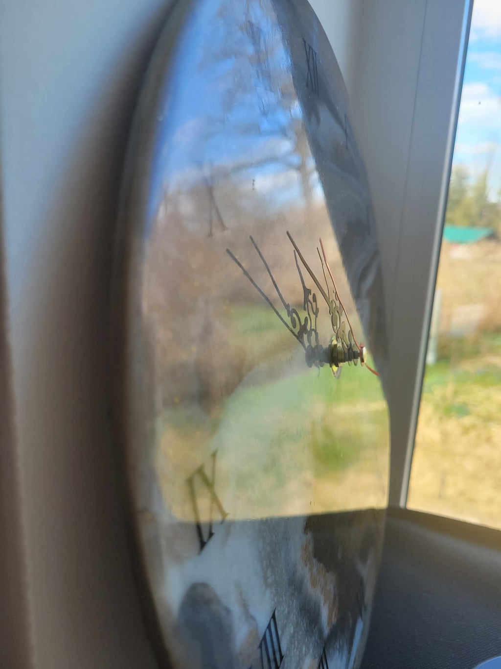 Reflection in a car side mirror of a rural landscape with trees and open fields.