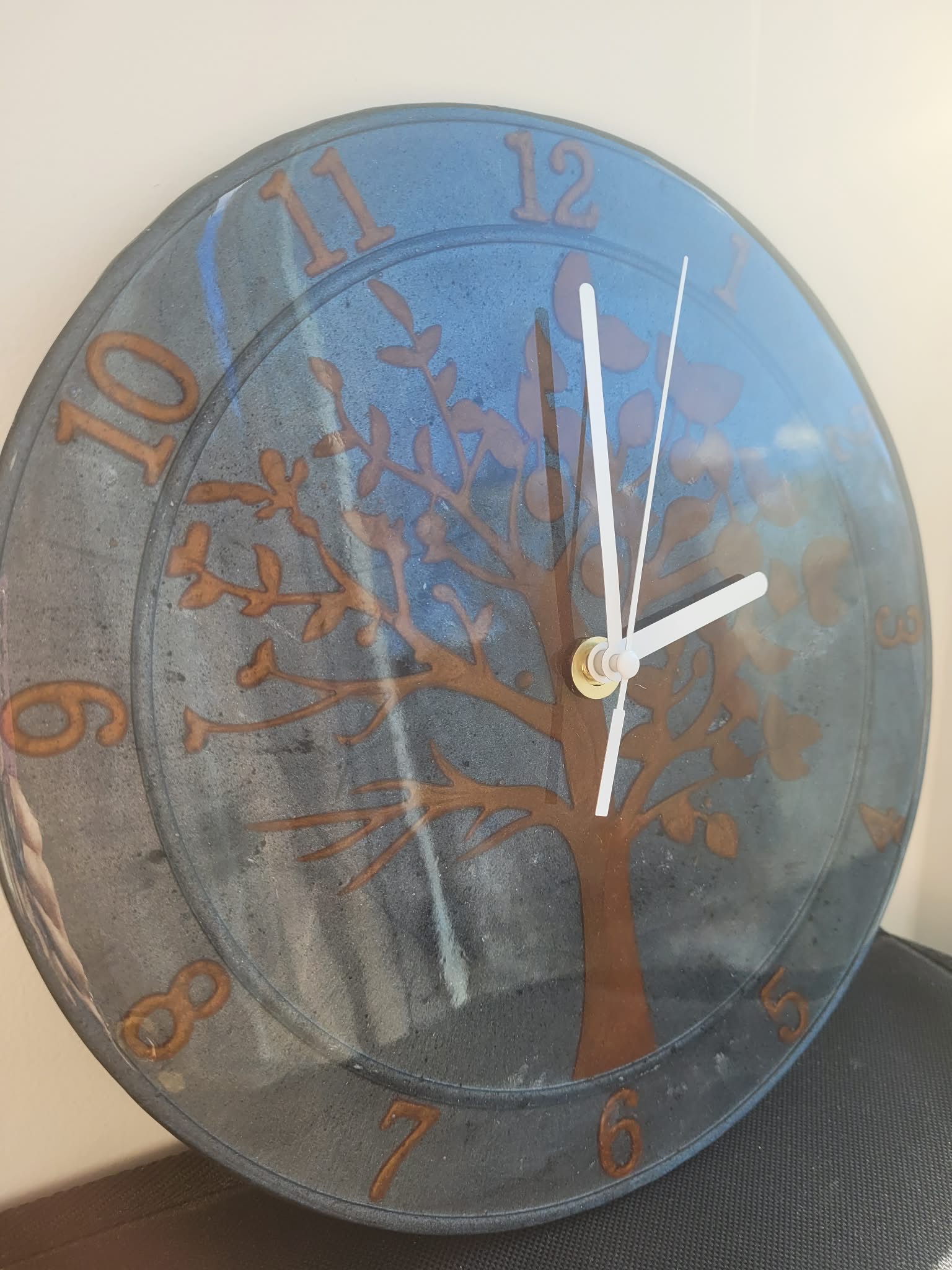 Wall clock with tree design and blue background