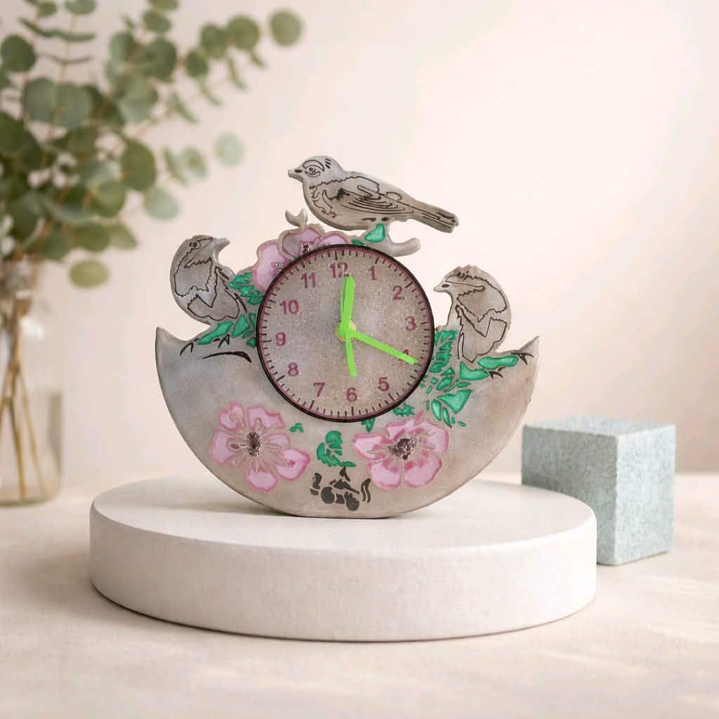 Decorative clock with birds and flowers on a white surface