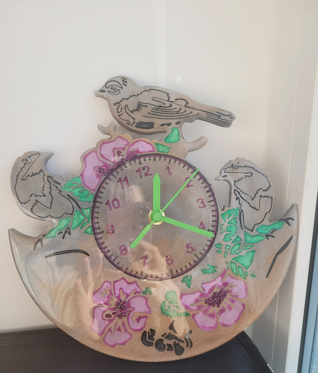Decorative wall clock with floral and bird designs on a white background
