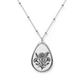 Teardrop-shaped pendant with floral design on a chain against a white background