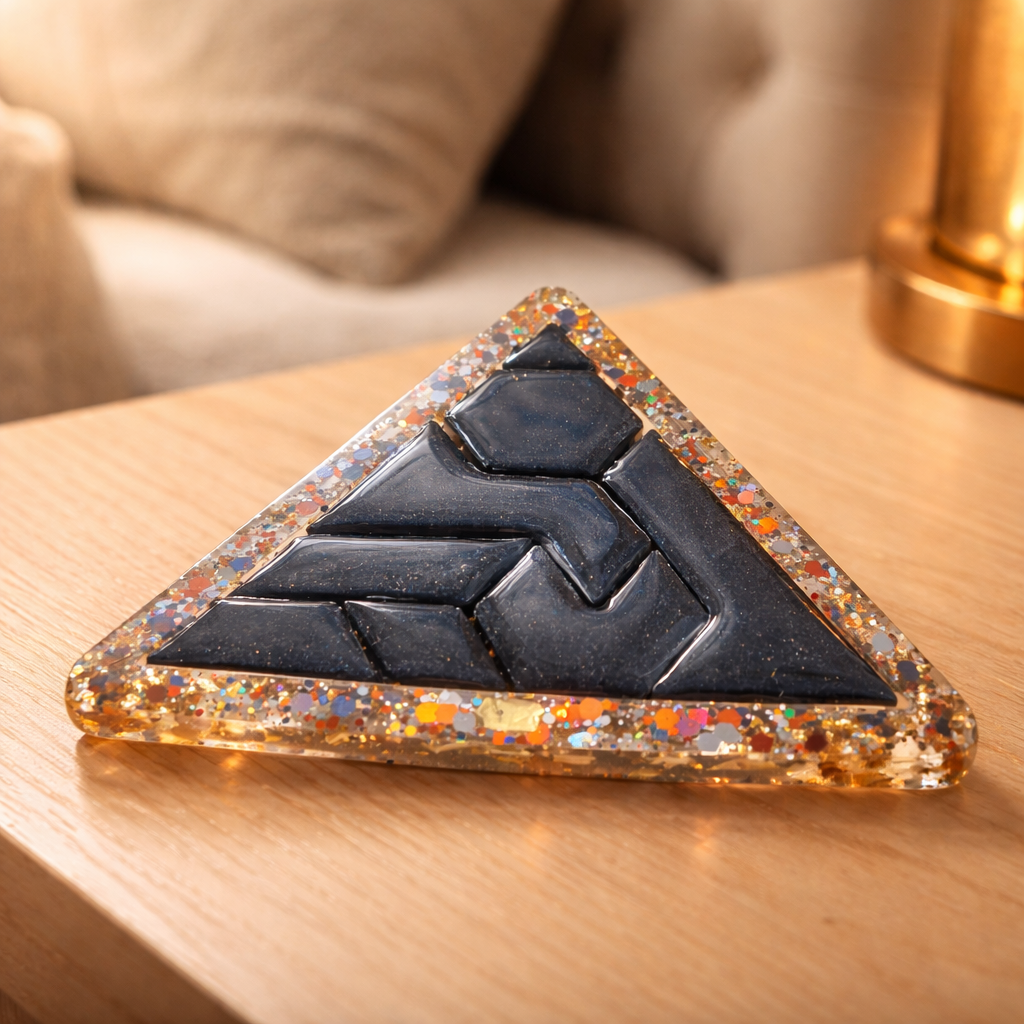 Triangular decorative item with a black geometric design on a wooden surface