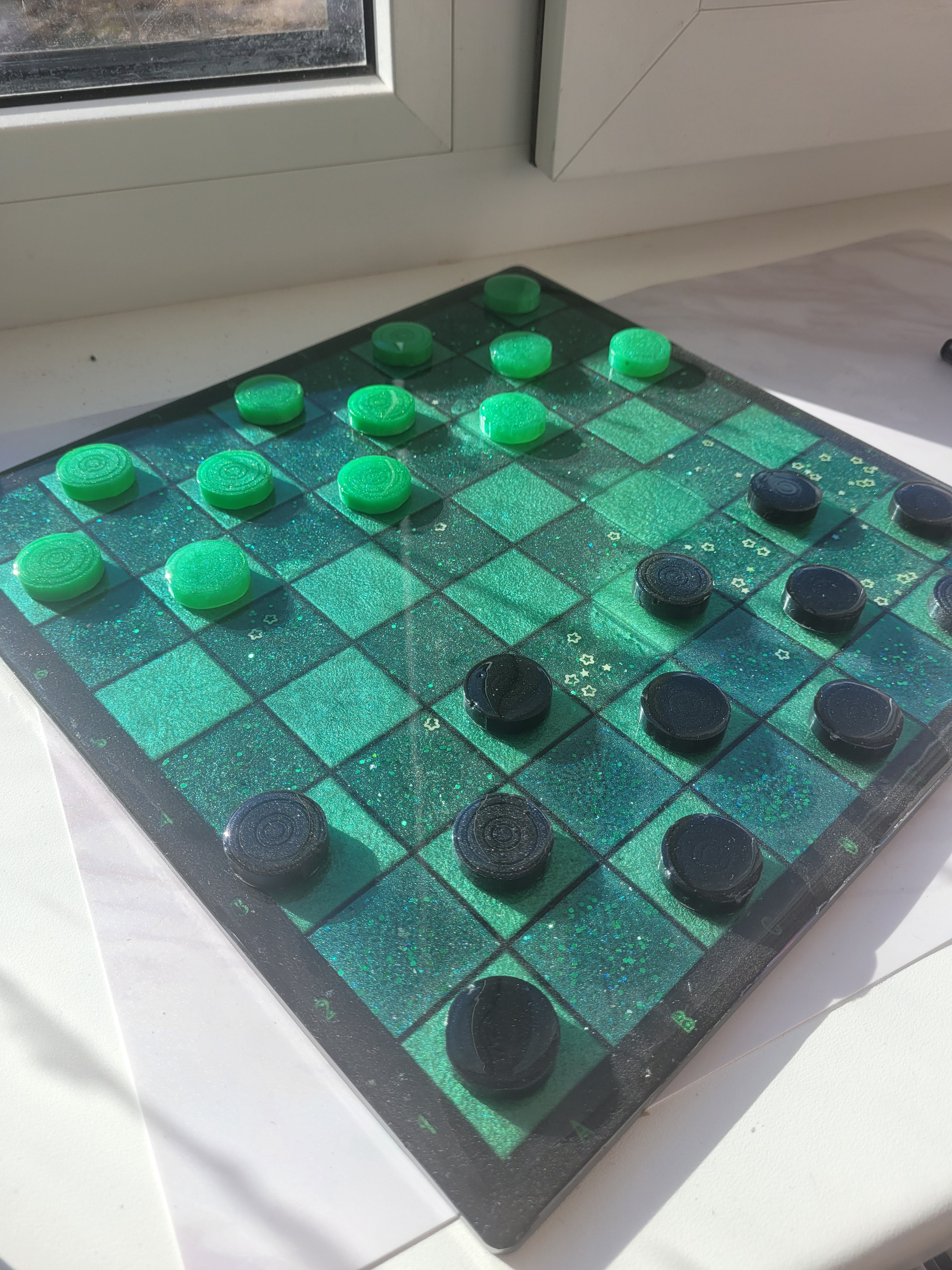 Checkered board with green and black pieces on a white surface