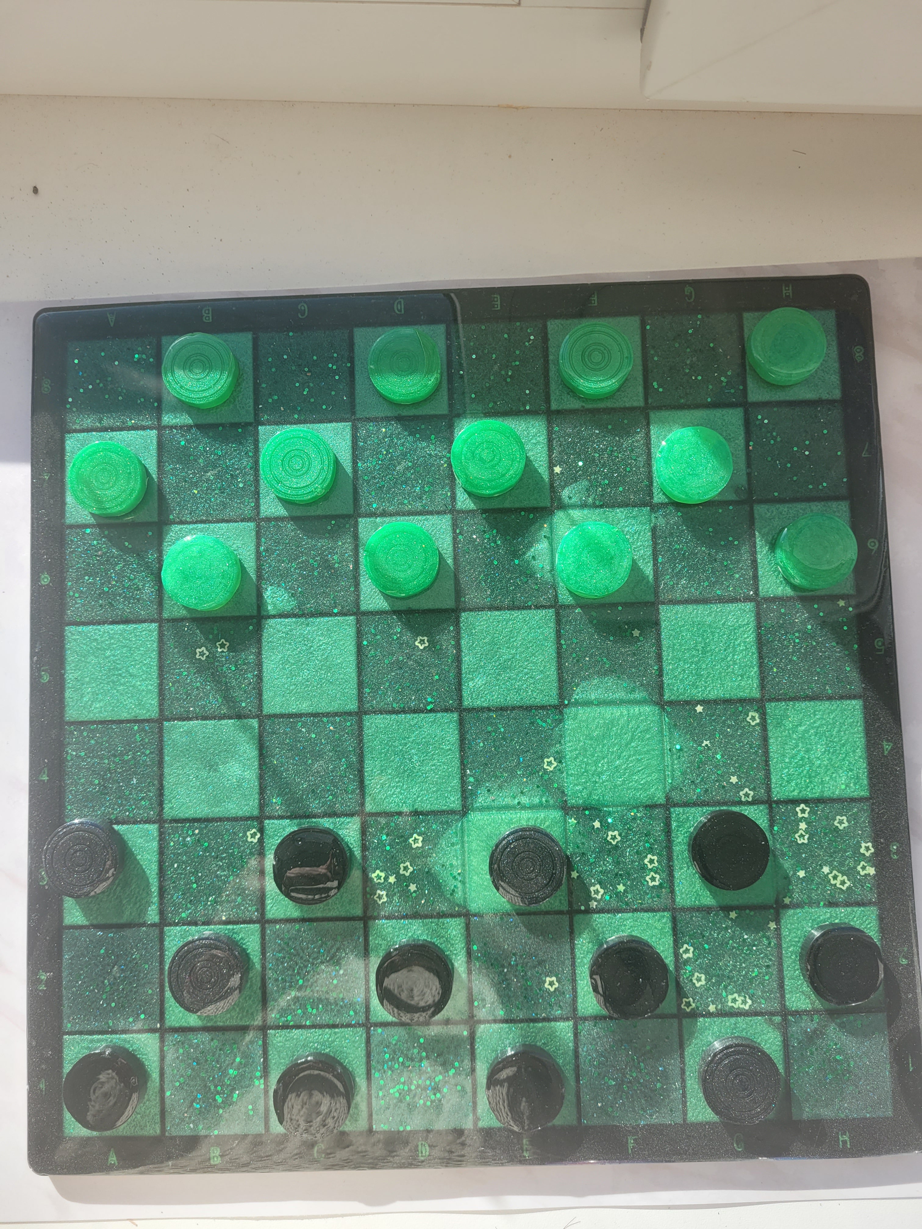Checkers board with green and black pieces on a white background
