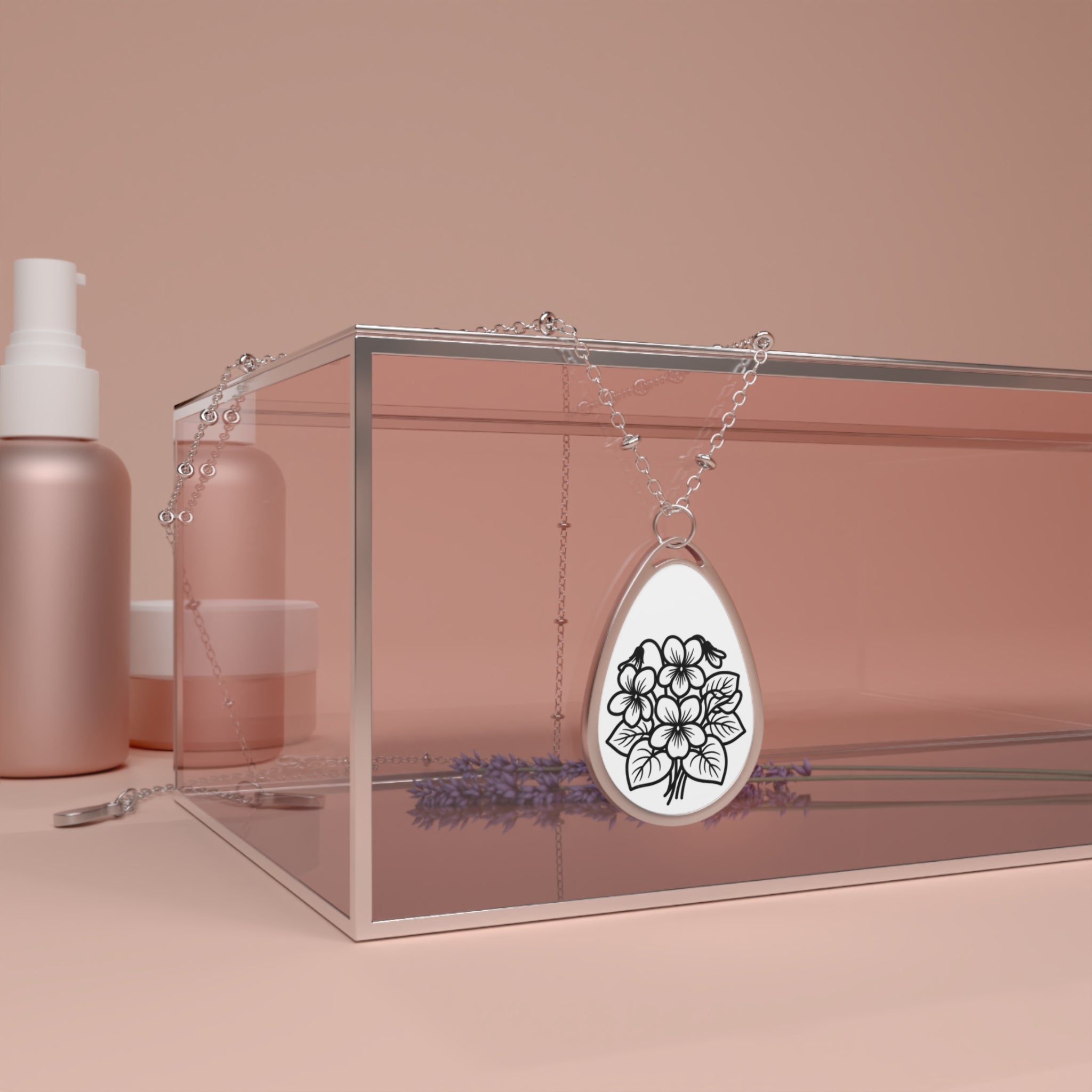 Silver teardrop pendant with floral design on a pink background