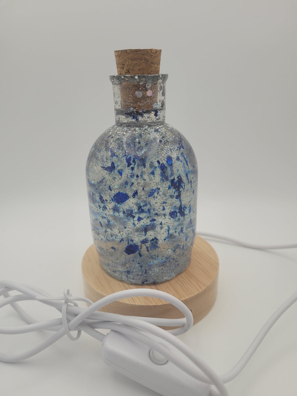 Decorative bottle with cork stopper and wooden base on a white background