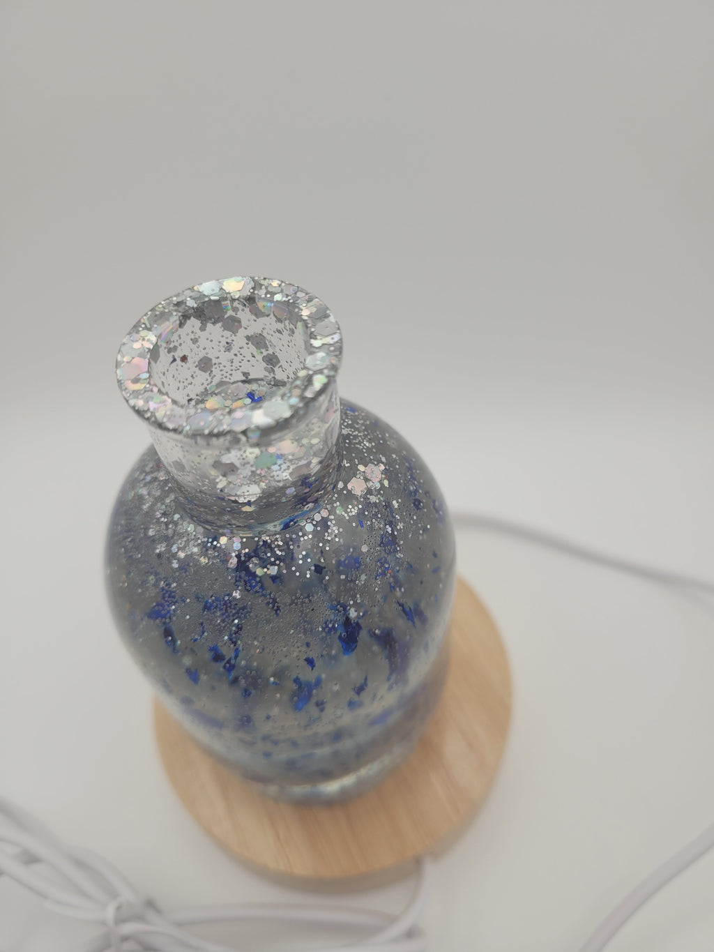 Decorative bottle with a wooden base on a light gray background