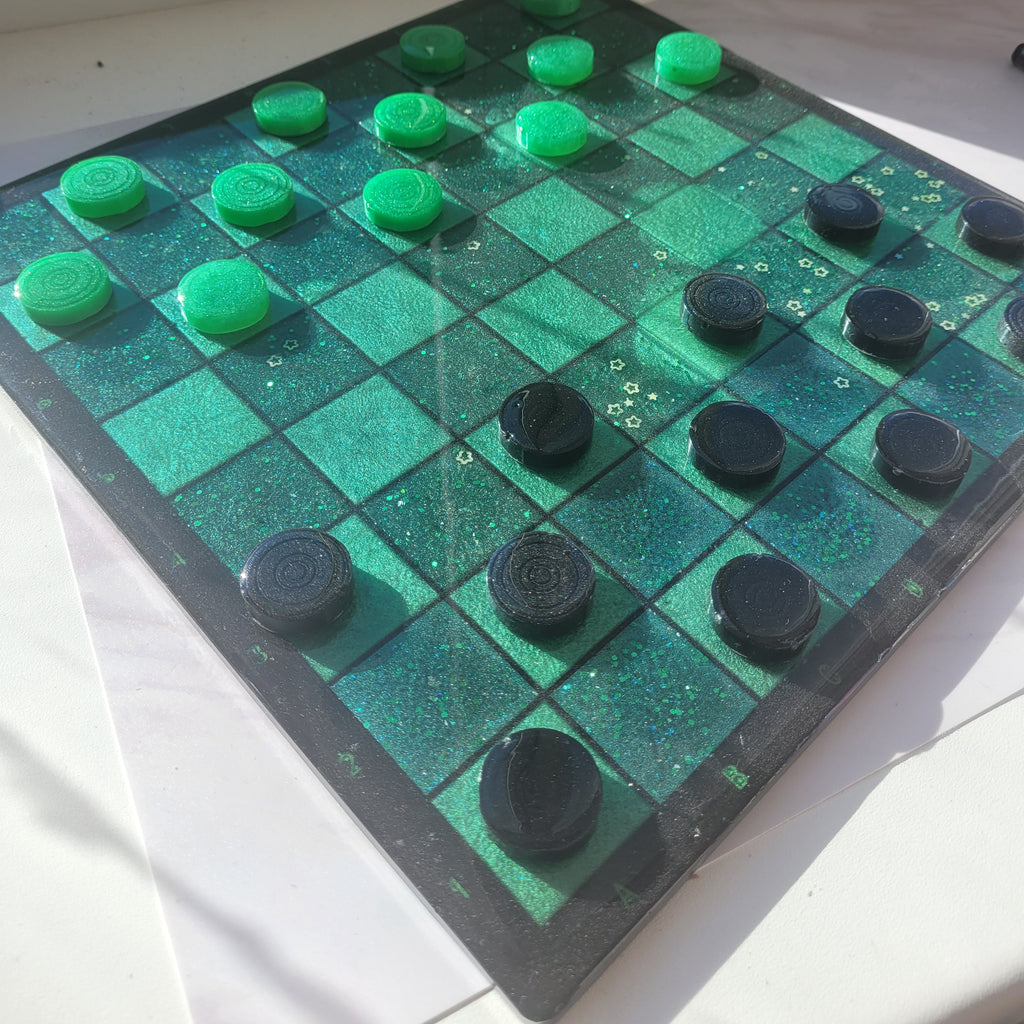 Checkered board with green and black pieces on a white surface
