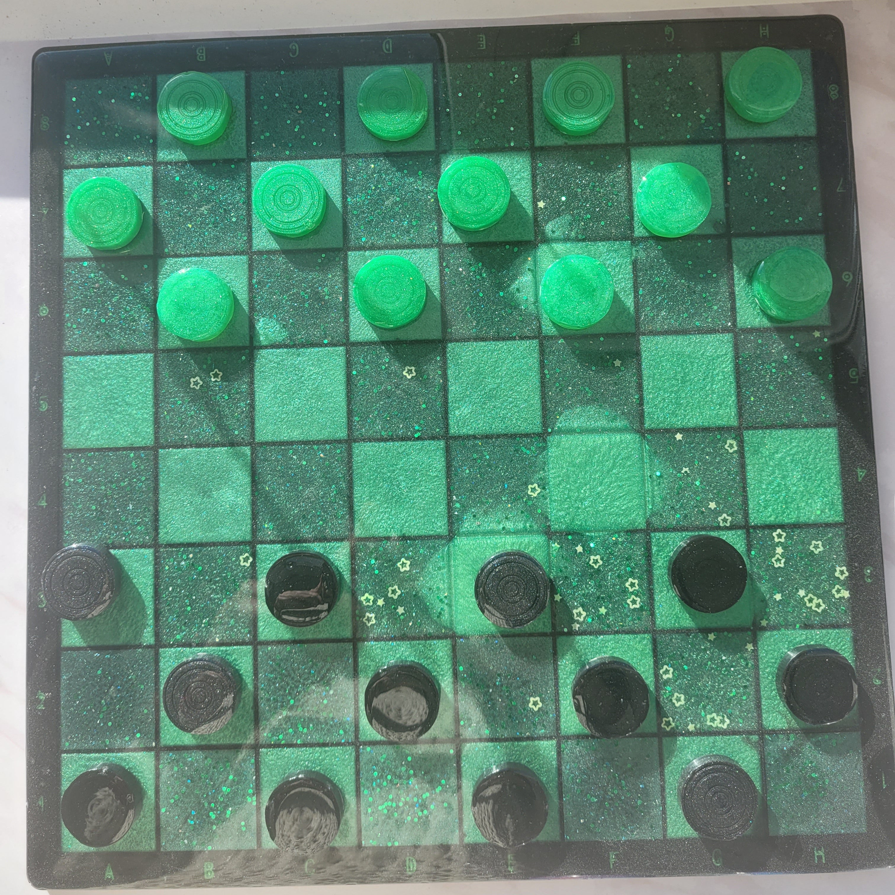 Checkers board with green and black pieces on a white background