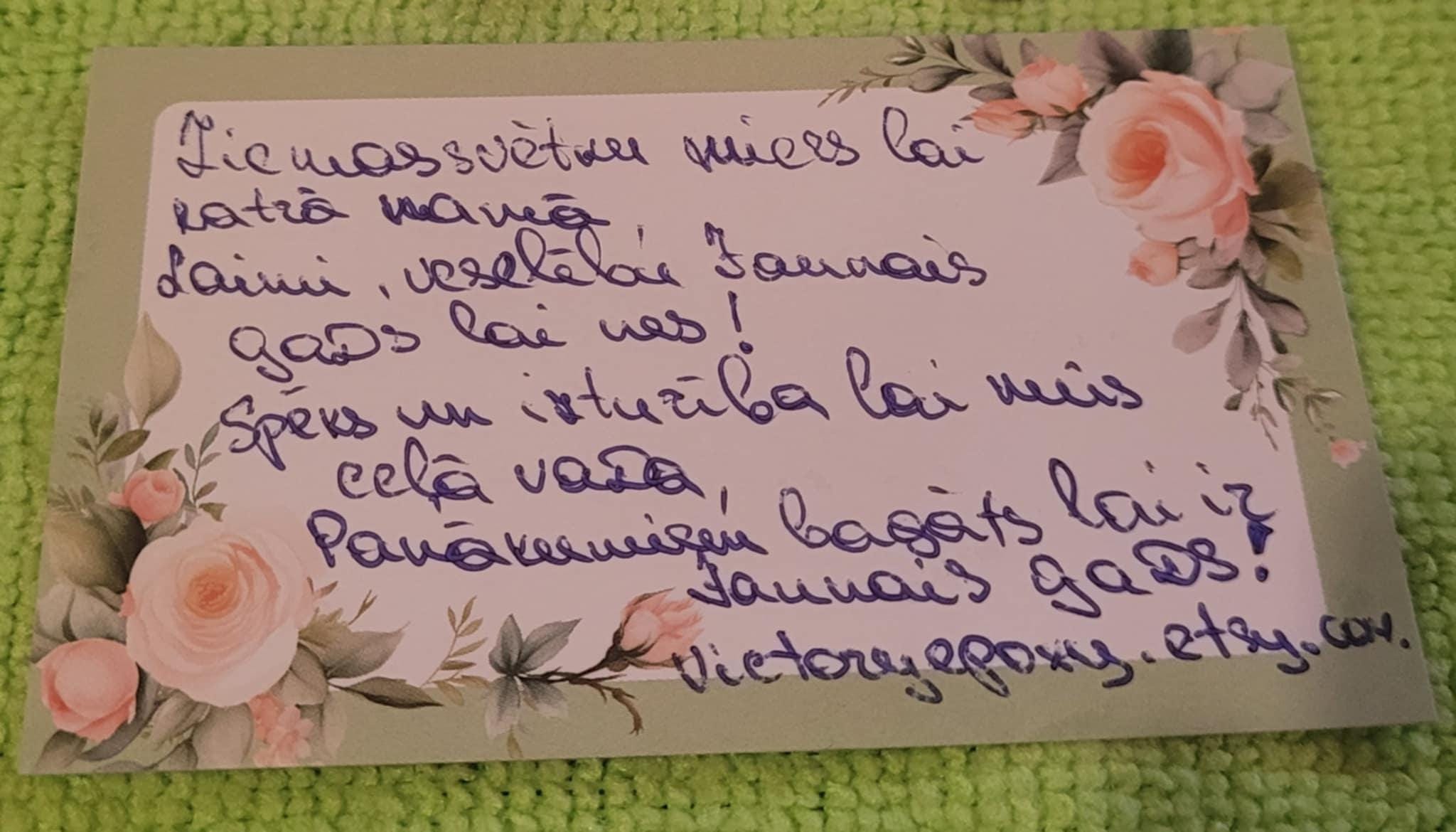 Handwritten message on a decorative card with floral elements on a textured green background