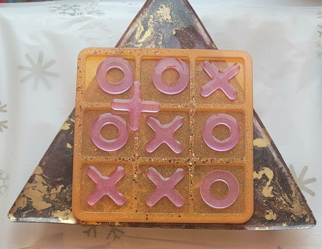 Tic-tac-toe game set with pink pieces on a decorative stone surface