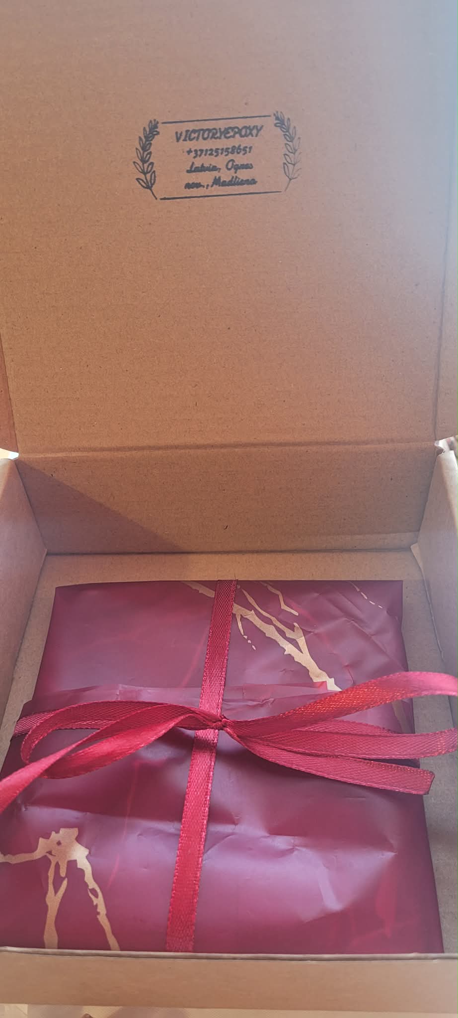 Gift wrapped in red paper with a red ribbon inside an open box.