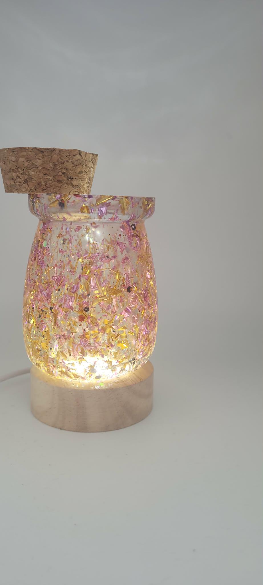 Decorative lamp with a glittery pink interior and wooden base on a plain background