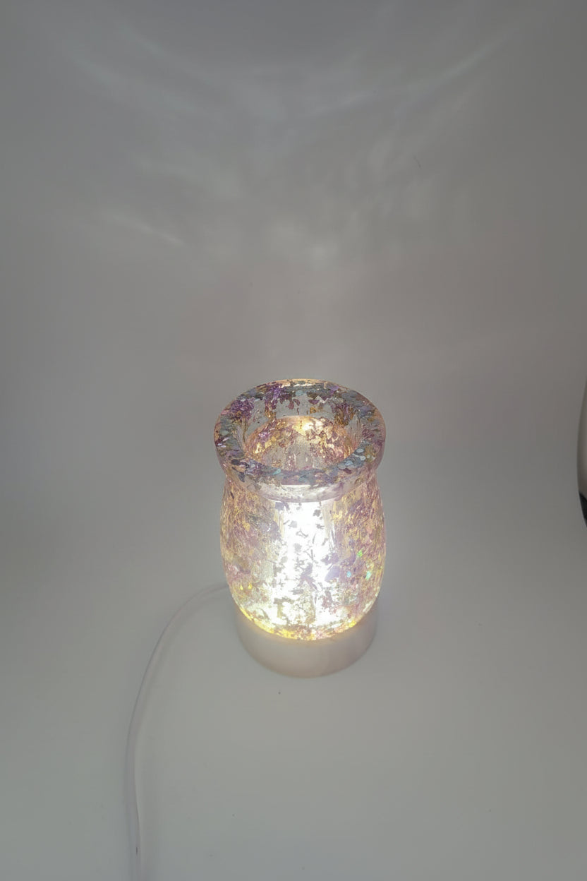 Illuminated glass jar with decorative top on a plain background