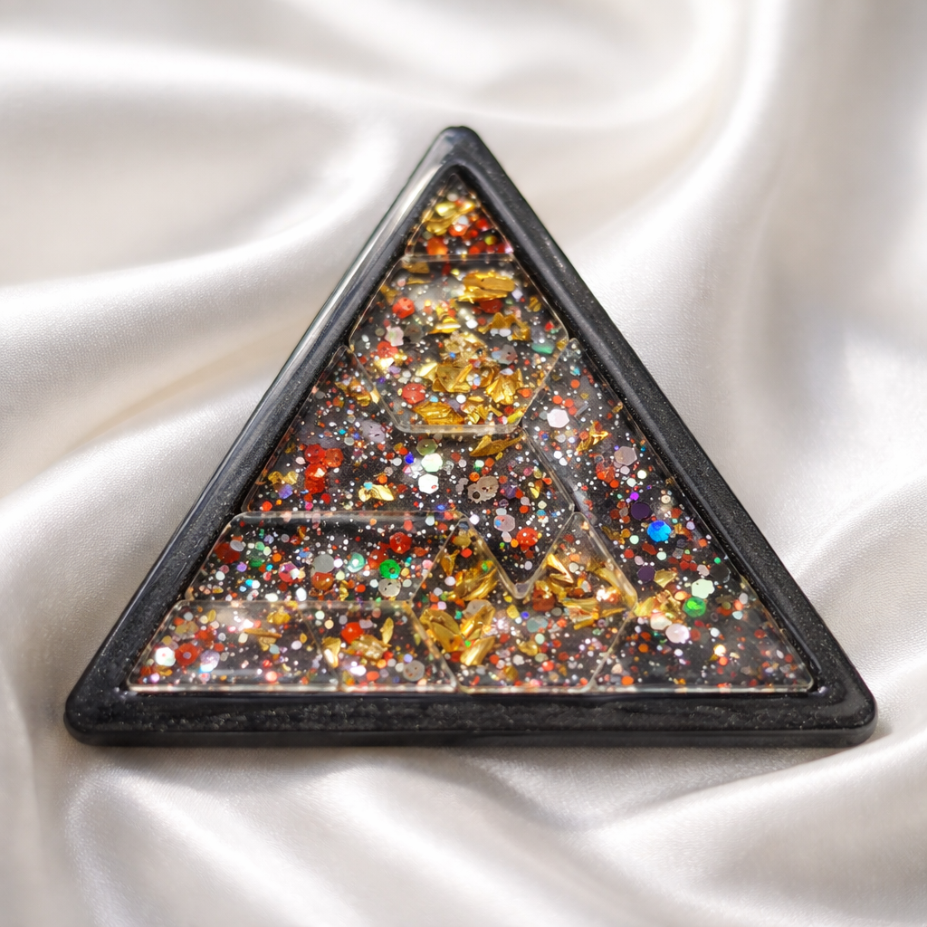 Triangular brooch with multicolored gemstones on a white fabric background