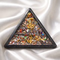 Triangular brooch with multicolored gemstones on a white fabric background