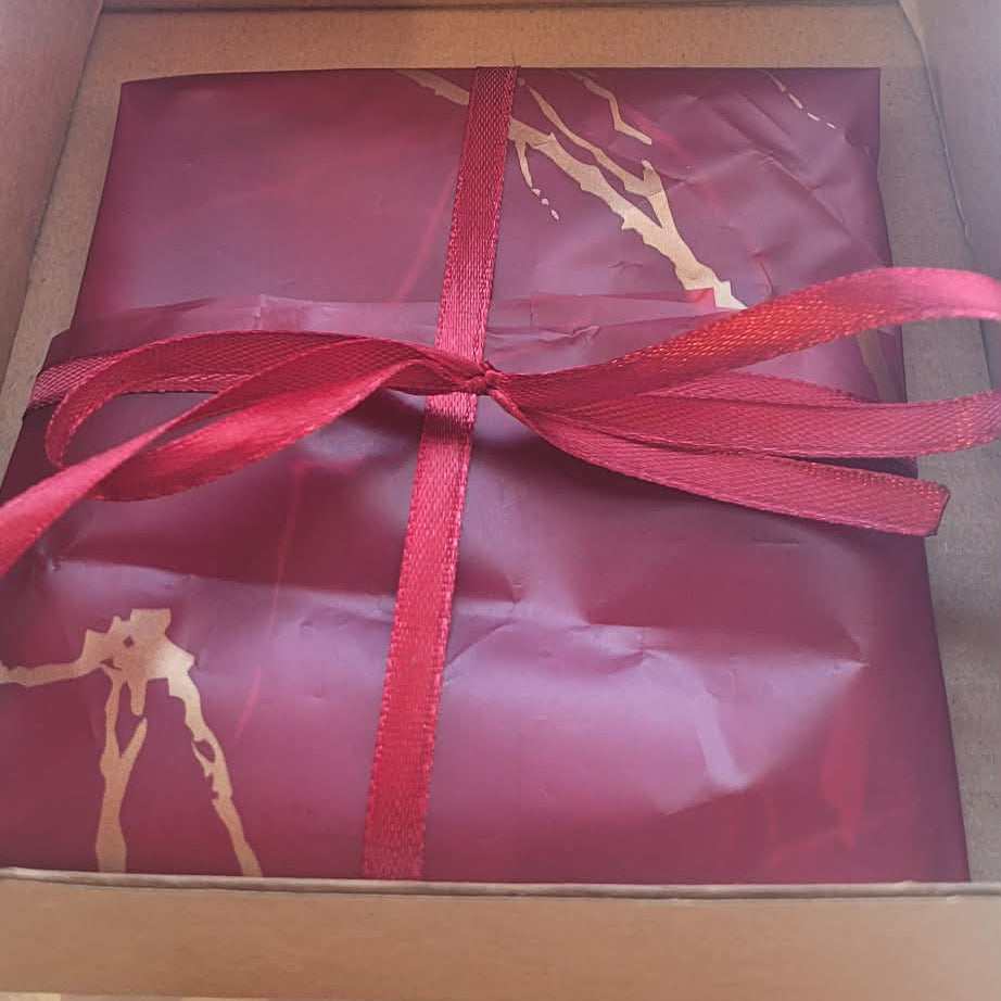 Gift wrapped in red paper with a red ribbon inside an open box.