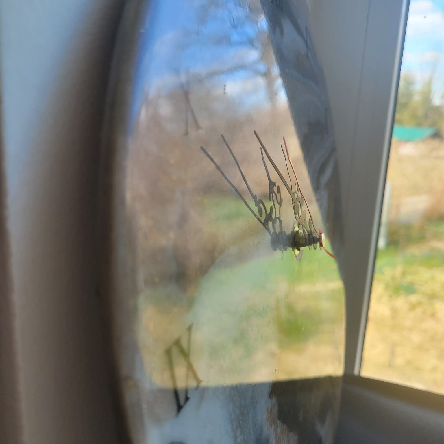 Reflection in a car side mirror of a rural landscape with trees and open fields.