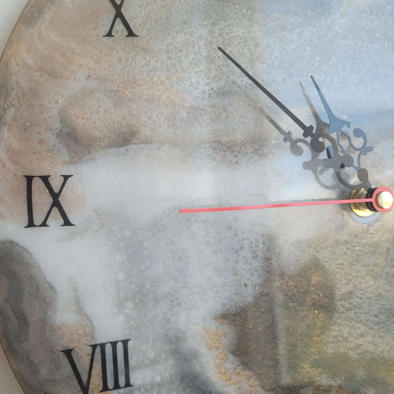 Close-up of a clock face with Roman numerals and a sword-like hand.