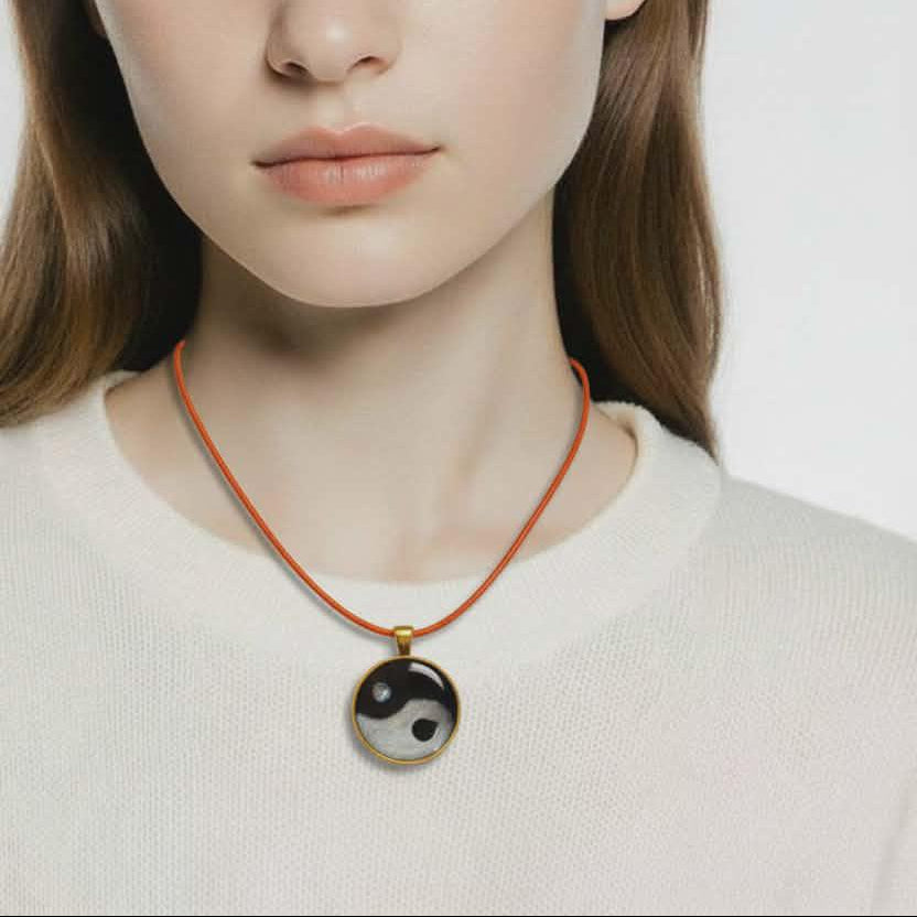 Woman wearing a necklace with a yin yang pendant against a plain background