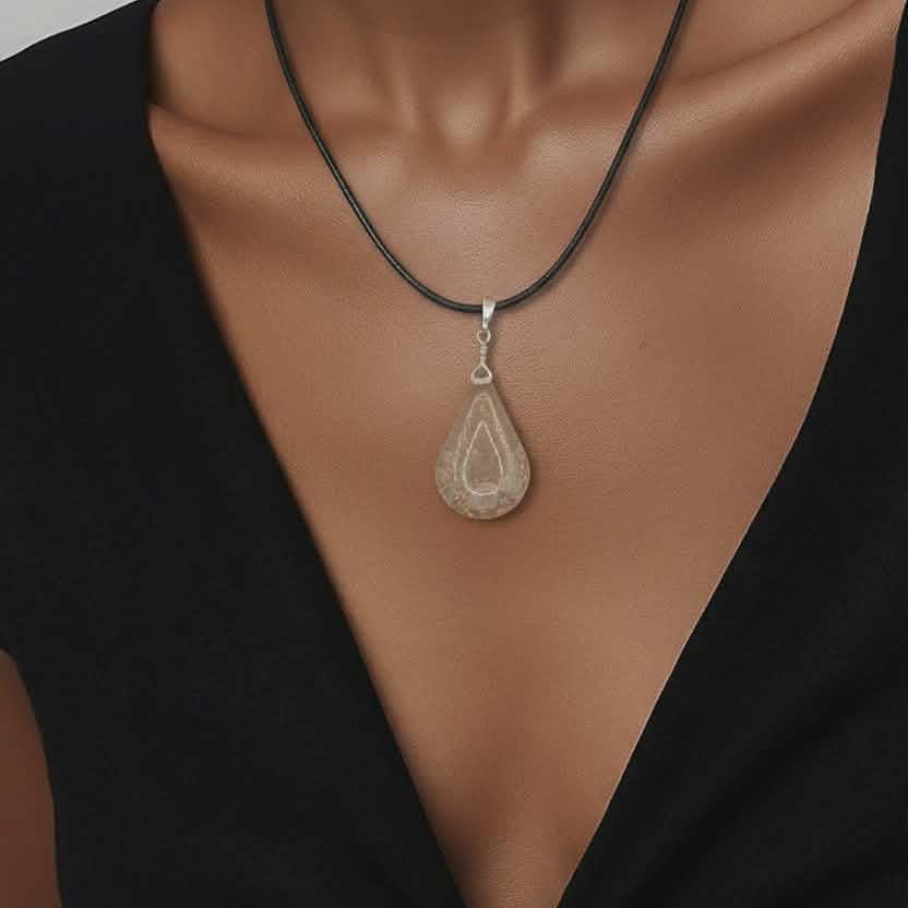 Gold necklace with a cross pendant on a person wearing a black top.