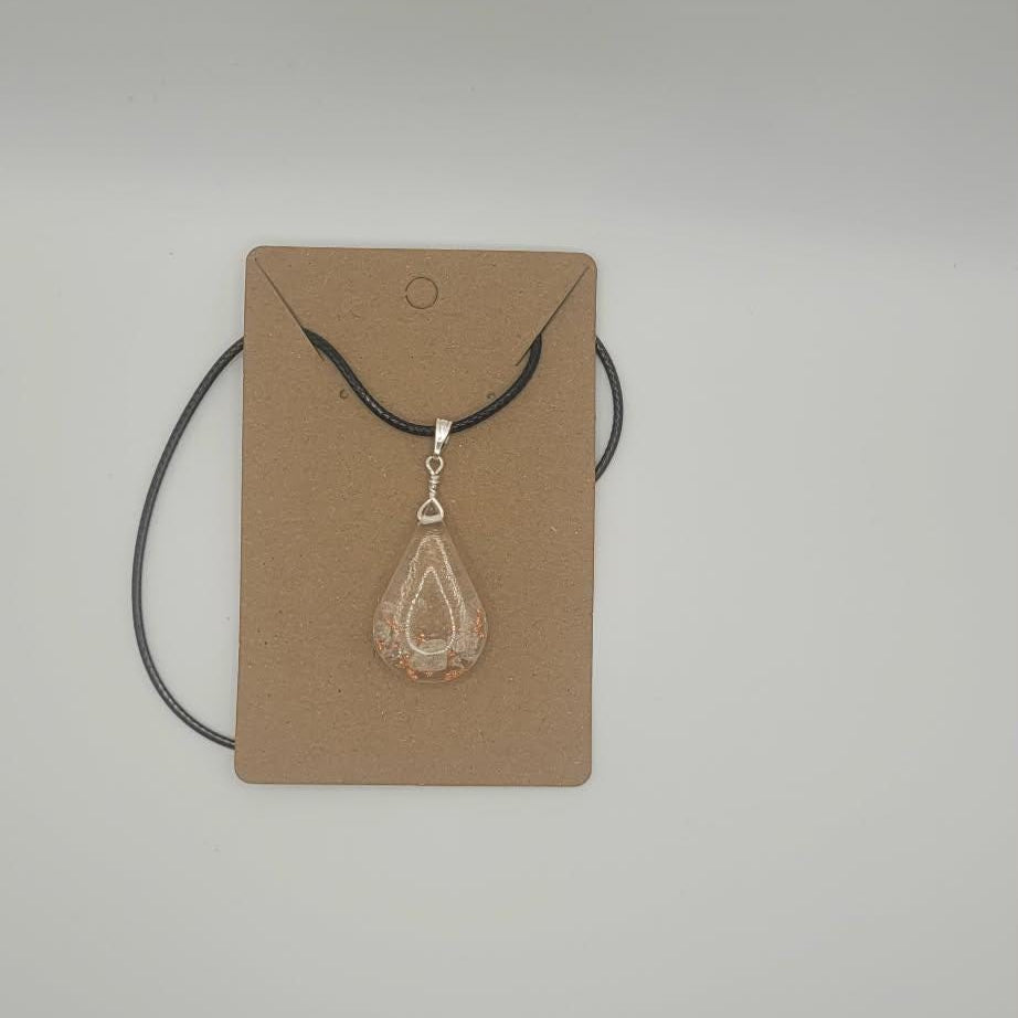 Jewelry pendant on a string with a cardboard backing against a plain background