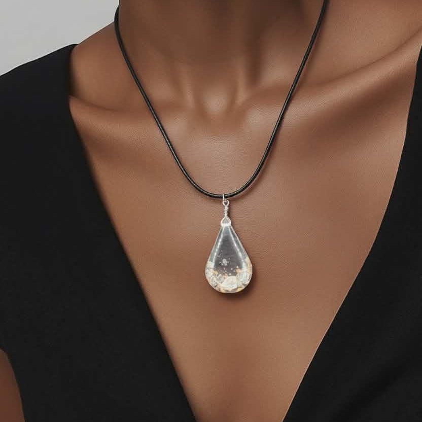 Teardrop-shaped pendant necklace on a black cord worn by a model in a black top.